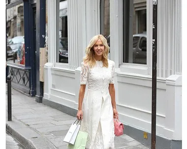 Woman in white dress walking with shopping bags in St Germain, Paris street.