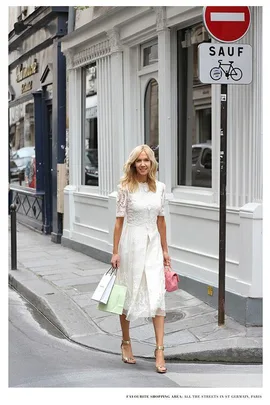 Woman in white dress walking with shopping bags in St Germain, Paris street.