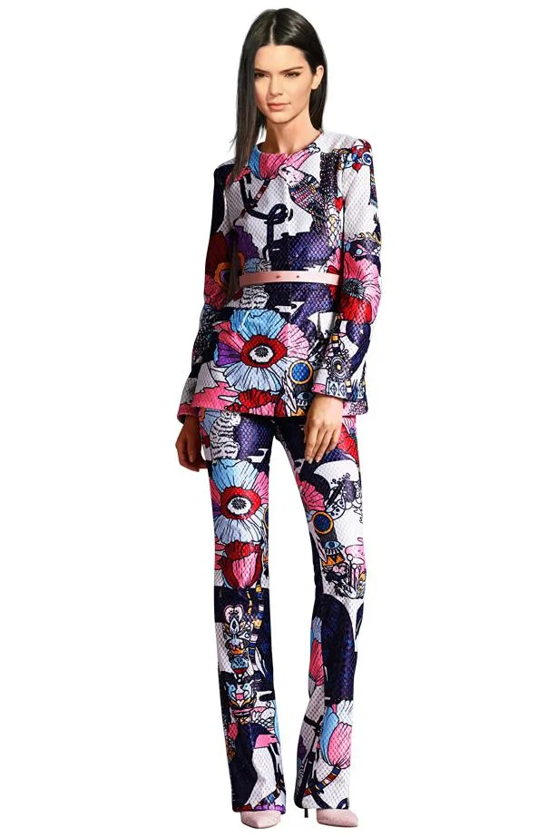 Model in a colorful, cartoon-print pantsuit with floral and abstract designs, posing confidently on a white background.