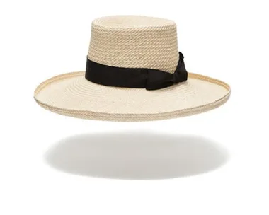 Straw hat with wide brim and black ribbon, floating over white background.