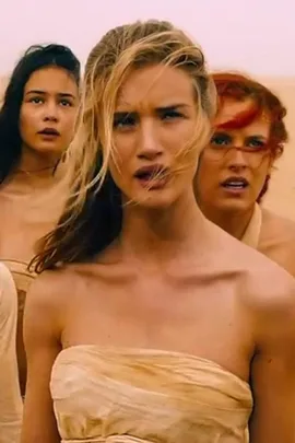 Scene from "Mad Max: Fury Road" with three women in desert attire, looking concerned.