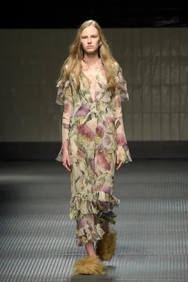 Model in a sheer floral dress and shaggy shoes on the Gucci runway.