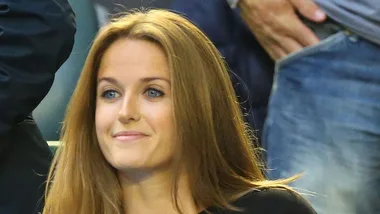 A woman with long, straight hair and a slight smile at a public event.