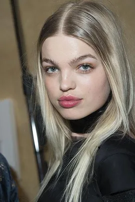 A model with long blonde hair and pink lips, showcasing a natural beauty look with subtle makeup.