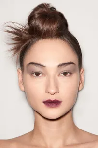 Model with an elegant top knot hairstyle, smoky eye makeup, and dark plum lipstick, showcasing a chic look from Marc Jacobs AW15 collection.