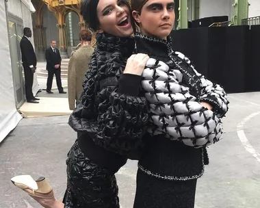 Two women in stylish outfits posing playfully at a fashion event, one smiling and the other serious.