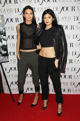 Kendall and Kylie Jenner standing together at a DuJour event on a red carpet.