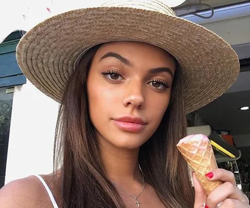 Woman in a wide-brimmed straw hat holding an ice cream cone.