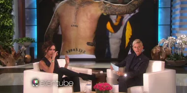 Victoria Beckham and Ellen DeGeneres on "The Ellen Show", with a large photo of David Beckham's back tattoos displayed behind them.