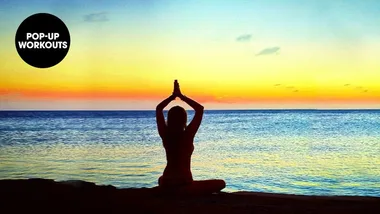 Person seated in yoga pose near ocean at sunset, "Pop-Up Workouts" text overlay in corner.