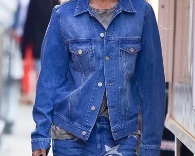 Woman in denim jacket and star-patterned jeans walking down a street.