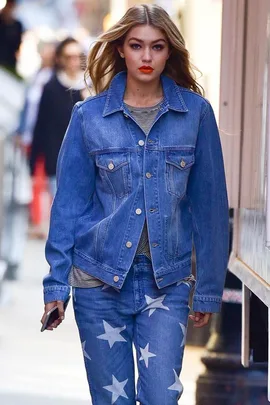 Woman in denim jacket and star-patterned jeans walking down a street.