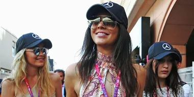 Three women wearing Mercedes-Benz caps and sunglasses, smiling and walking outside a Monaco event.