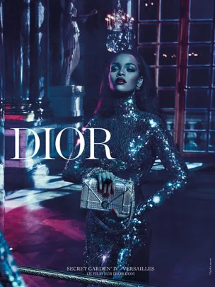 Rihanna in a sparkling, blue dress holding a Dior handbag, featured in the Dior "Secret Garden IV Versailles" campaign.