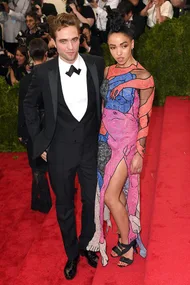 Two individuals on the Met Gala red carpet, with one wearing a pink dress featuring an abstract artistic design.