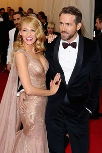 Blake Lively in a metallic gown and Ryan Reynolds in a tuxedo pose together at the Met Gala on the red carpet.