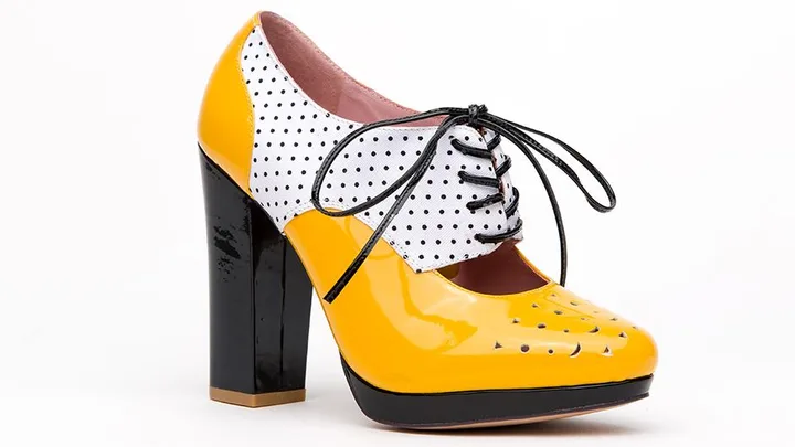 Yellow and white polka-dot high-heeled shoe with black laces and black thick heel, inspired by Mad Men.