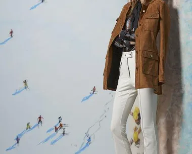 Model in suede jacket and white flared pants with a ski-themed backdrop from Resort 2016 fashion collection.