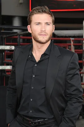 Man in a black suit with a beard and mustache at an event.