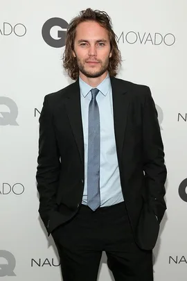 A man in a suit stands with his hands in his pockets at a GQ event backdrop.