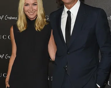 Frida Giannini and Patrizio di Marco smiling at a Gucci event, both dressed formally in black.