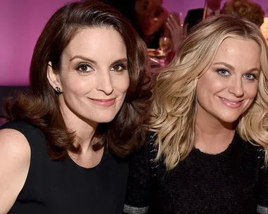 Actresses Tina Fey and Amy Poehler smiling together at an event.