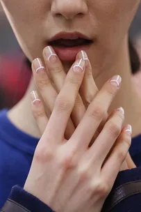 A close-up of a person's elaborate manicure adorned with fine white lines and circles on natural nails.