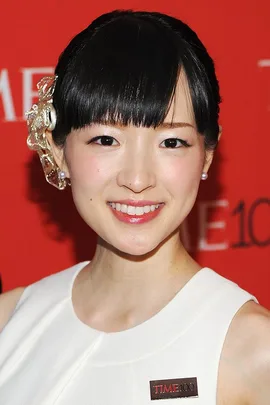 Woman in white dress with a TIME100 badge, smiling at a red carpet event.