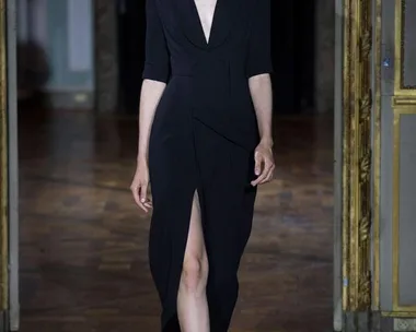 Model walks runway in a black dress with a deep V-neck and slit, wearing embellished eyewear, Ulyana Sergeenko AW15-16.