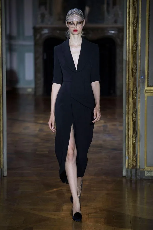 Model walks runway in a black dress with a deep V-neck and slit, wearing embellished eyewear, Ulyana Sergeenko AW15-16.