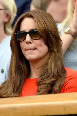 A woman with long brown hair wearing sunglasses and a red outfit at Wimbledon.