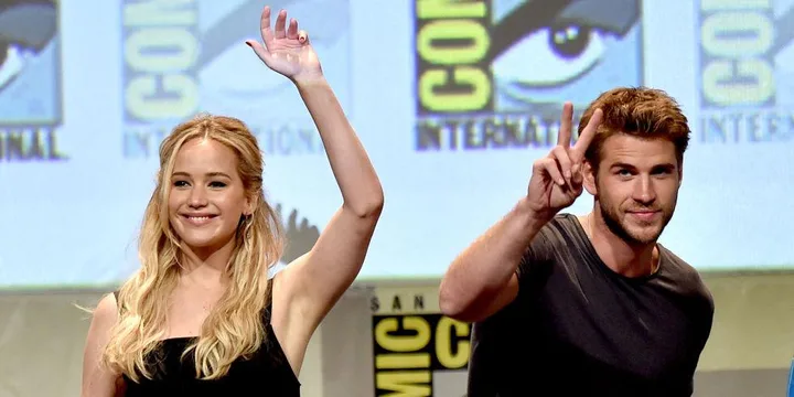 Jennifer Lawrence and Liam Hemsworth wave at Comic-Con International.