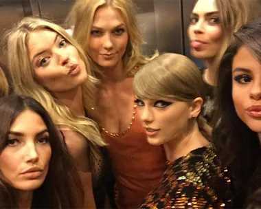 A group of six women posing playfully in an elevator at the VMAs, with some puckering and smiling for a selfie.