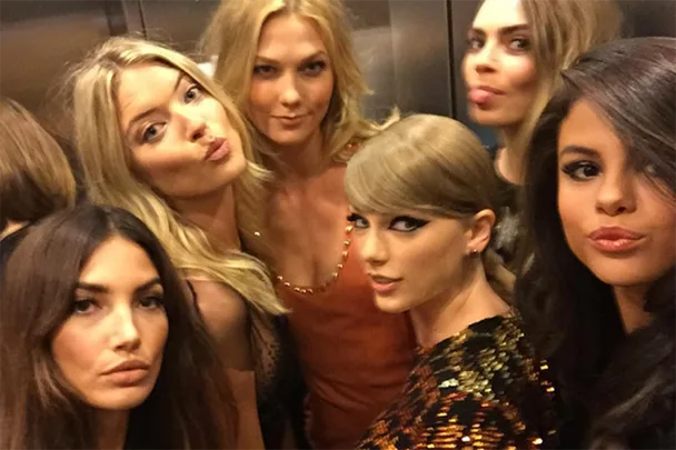 A group of six women posing playfully in an elevator at the VMAs, with some puckering and smiling for a selfie.