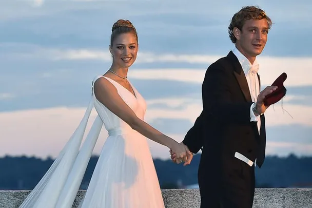 Beatrice Borromeo in an Armani wedding gown, holding hands with her partner outdoors during their wedding ceremony.