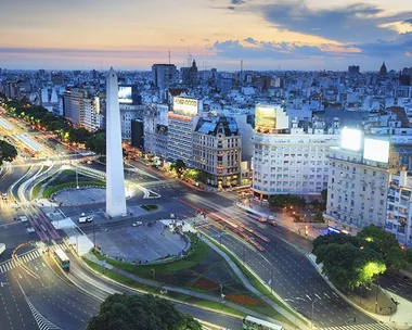 Aerial view of the Obelisk of Buenos Aires and surrounding buildings and streets at dusk.