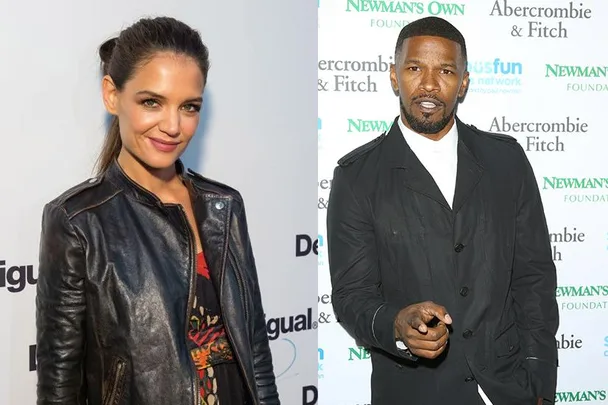 Katie Holmes in a black leather jacket and Jamie Foxx in a suit, standing in front of promotional backdrops.