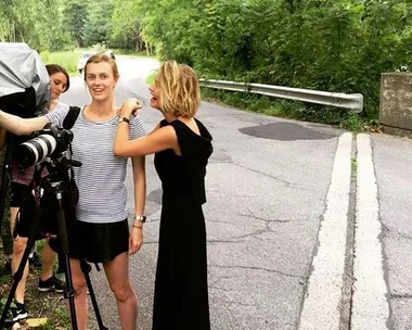 Model and crew setting up a photoshoot on a tree-lined roadside.