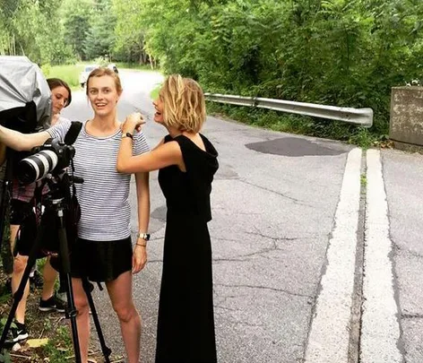 Model and crew setting up a photoshoot on a tree-lined roadside.