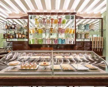 Display case with assorted pastries and desserts, and shelves filled with colorful glass jars of candies at Marchesi Pasticceria.