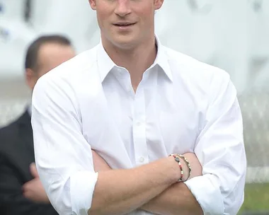 Prince Harry in a white shirt, arms crossed, standing outdoors, celebrating his 31st birthday.