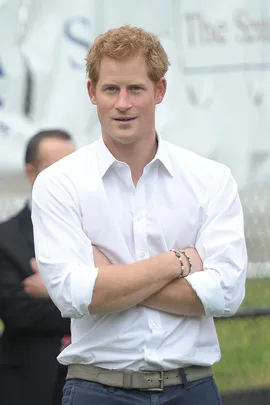 Prince Harry in a white shirt, arms crossed, standing outdoors, celebrating his 31st birthday.