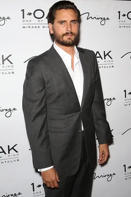 A man in a suit stands against a backdrop with text "1 OAK" and "Mirage."