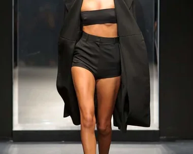 Model in black bandeau, shorts, and coat walks runway at Vera Wang SS16 fashion show.