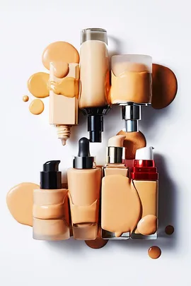 Various foundation bottles and spills displayed on a white background.