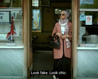 A stylish woman in a hijab and sunglasses stands at a shop entrance, with a sign reading "PALACE" inside. Subtitles: "Look fake. Look chic."