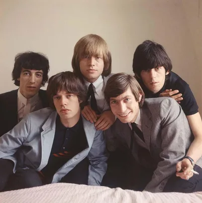 A classic band from the 60s posing together, dressed in suits with varying expressions, against a plain background.