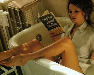 A woman in a bathtub reading "Help Your Husband Get Ahead" while smoking.