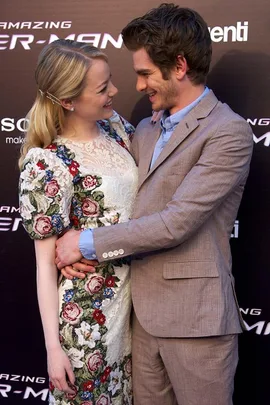 Actors from "The Amazing Spider-Man" smile at each other on the red carpet, embraced closely, wearing formal attire.