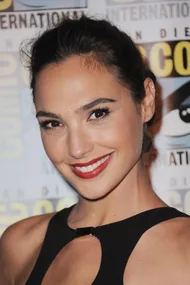 Actress at San Diego Comic-Con wearing a black dress, smiling with red lipstick and hair tied back.